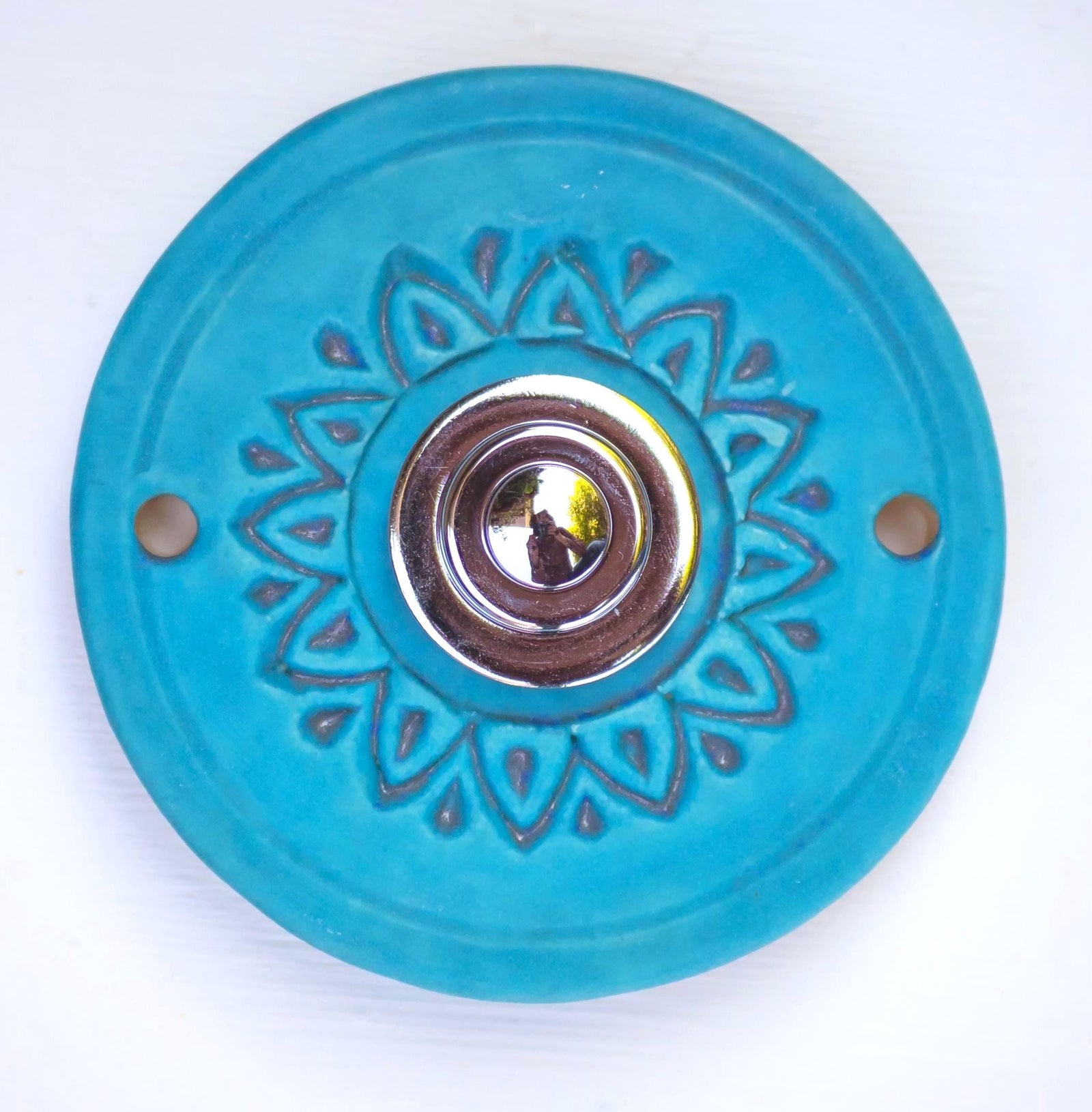 Runde dekorative Klingel mit geprägtem Blumen-Sternmuster auf reiner blauer Platte und silbernem Druckknopf in der Mitte