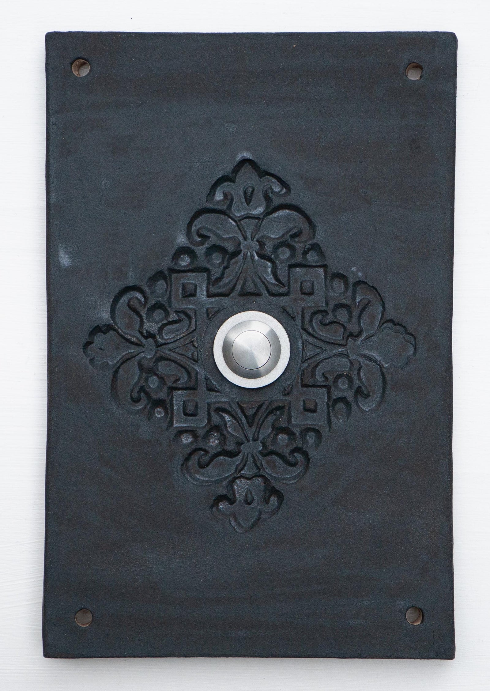 Rein schwarze Keramik-Klingelplatte mit erhabenem ornamentalem Blumenmuster und mittigem Silberknopf.