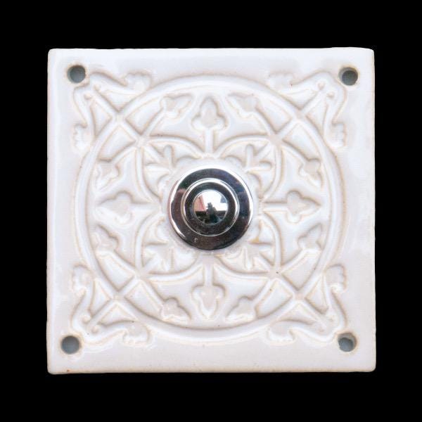 Quadratische dekorative Keramikklingel mit geprägtem floralen Mandala-Muster in Reinweiß und silbernem Druckknopf in der Mitte