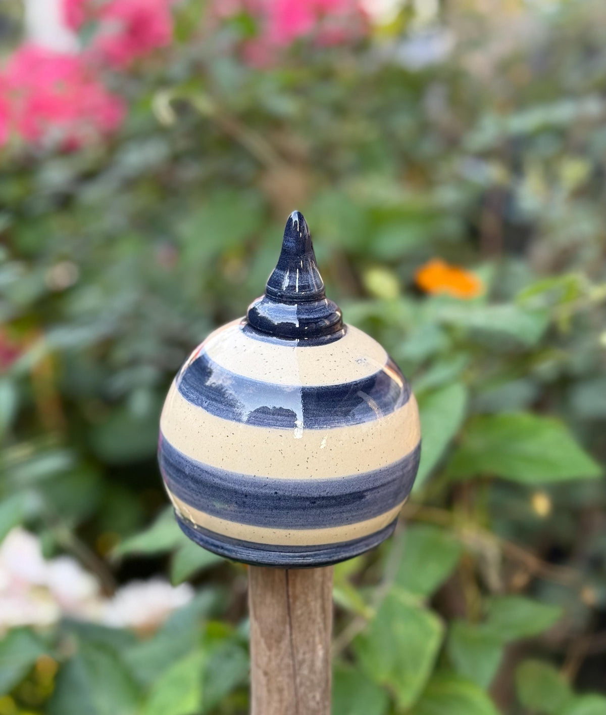 Handgefertigte Keramik-Gartenkugel mit blauen und cremefarbenen Streifen. Ideal als dekorativer Aufsatz für Gartenstäbe und Zäune.