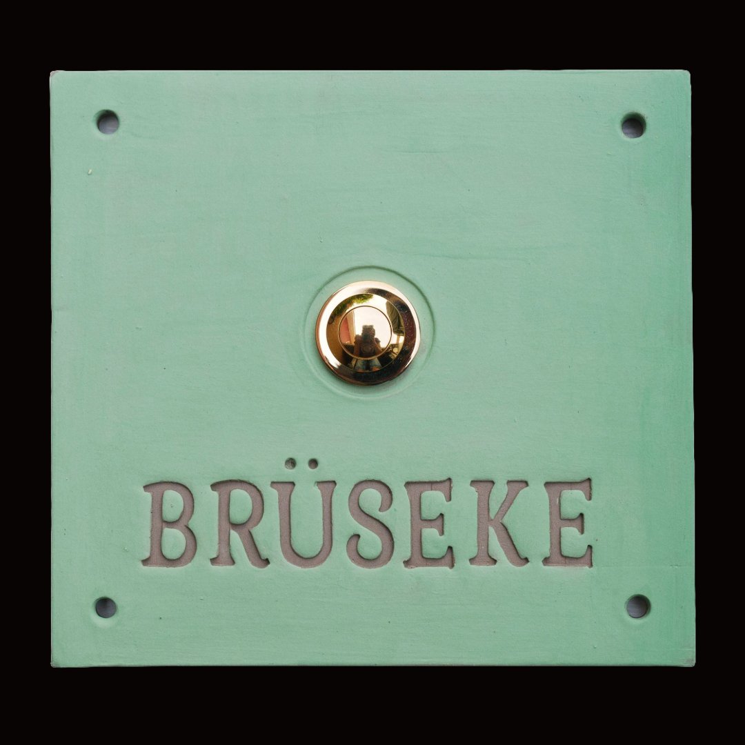 Quadratisches mintgrünes Keramik-Türklingelschild mit graviertem Familiennamen Brüseke und goldenem Knopf
