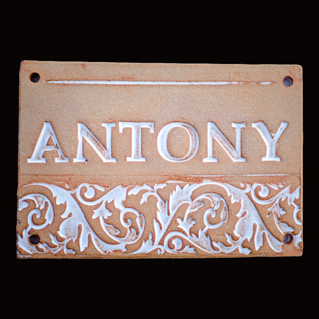 Rechteckiges Terrakotta-Keramik-Namensschild mit weißem Ornamentmuster und Schriftzug Antony