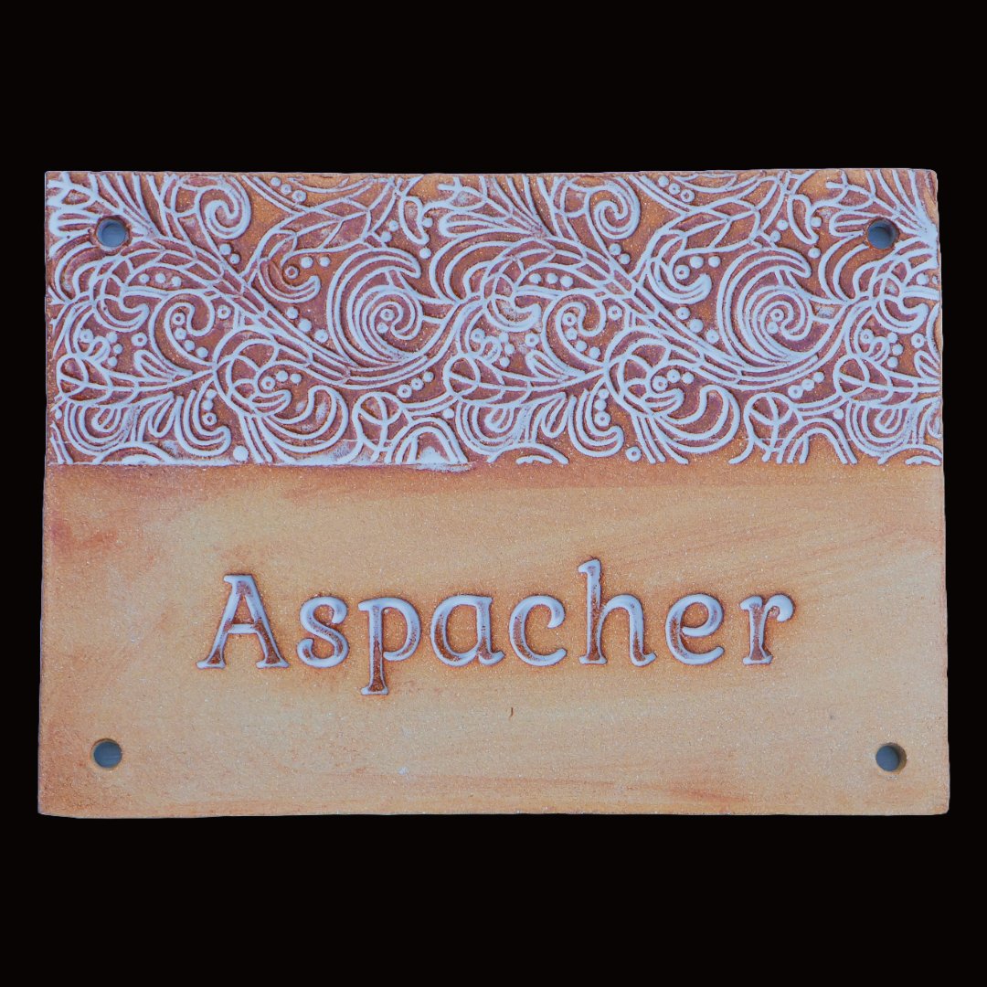 Handgefertigtes Terrakotta-Hausschild mit dekorativen weißen Verzierungen und Gravur Aspacher