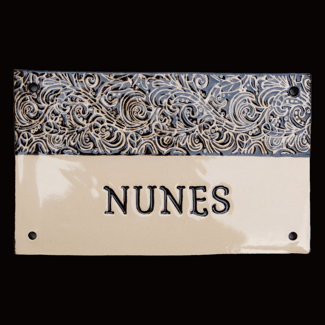Rechteckiges beiges Keramik-Namensschild mit kunstvollem schwarzem Wirbelmuster und eingraviertem Familiennamen Nunes