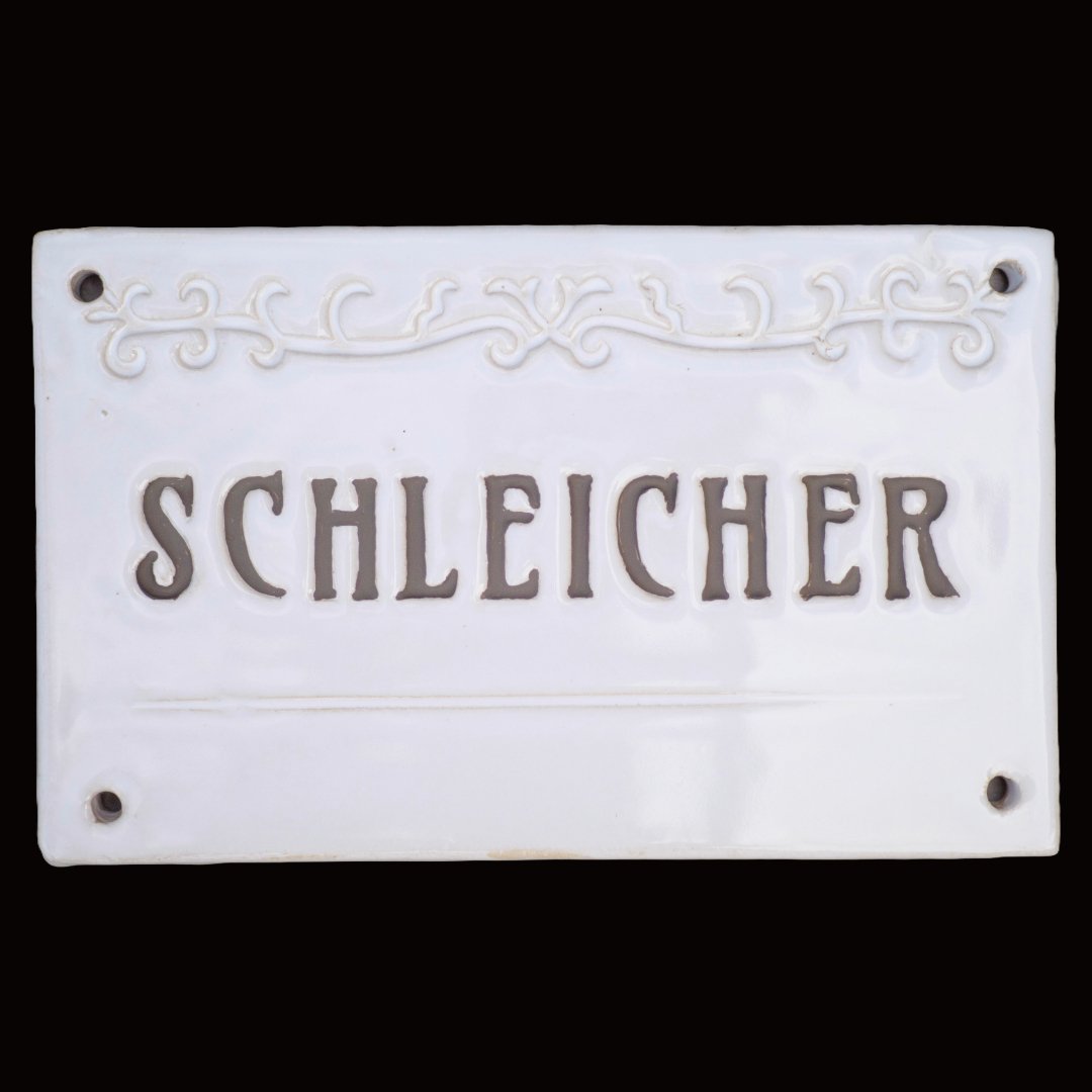 Handgefertigtes weißes Namensschild mit dunkelgrauer Inschrift Schleicher und Zierornament