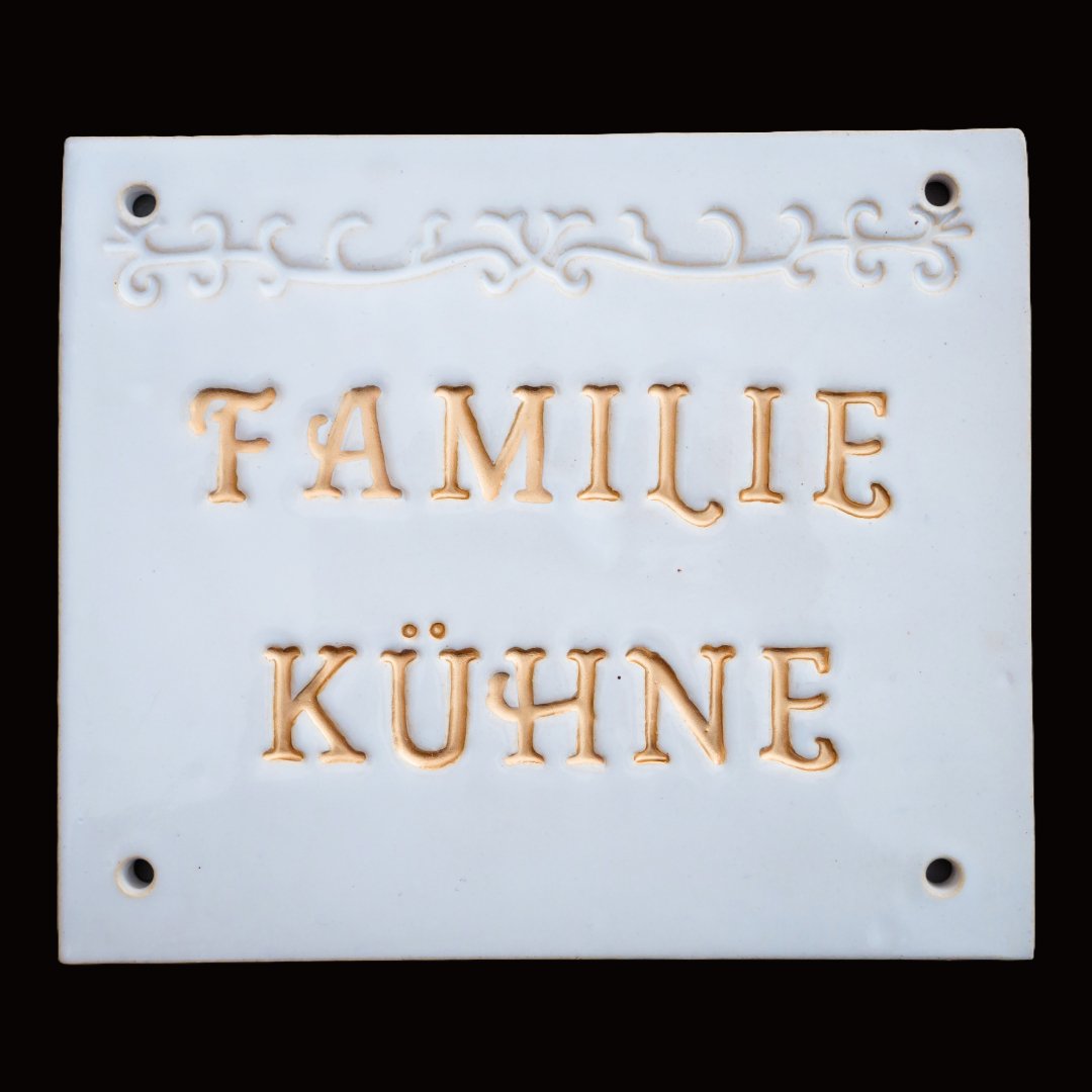 Handgefertigtes weißes Namensschild mit goldbrauner Inschrift Familie Kühne und Zierornament