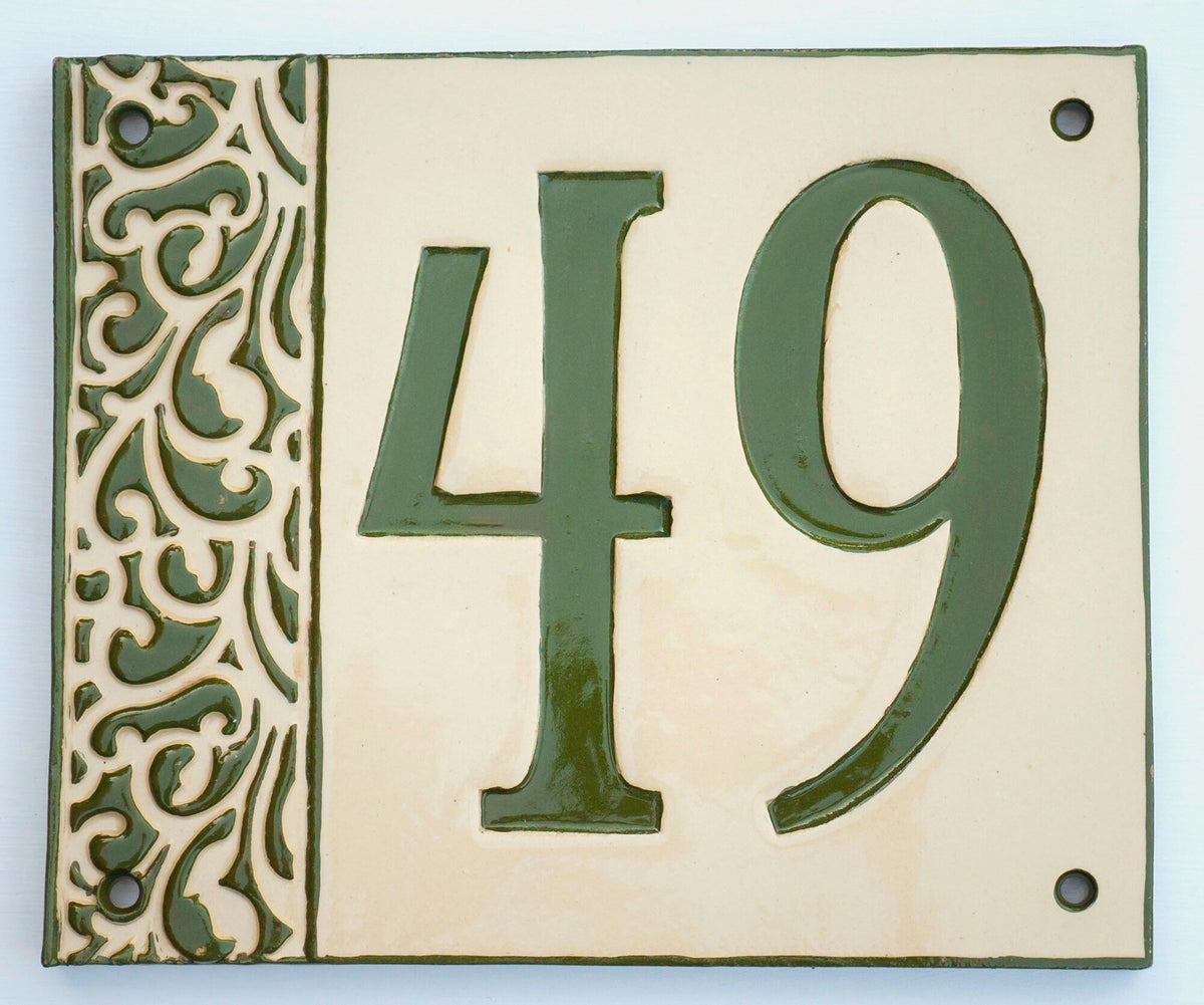 Rechteckiges Keramik-Hausschild mit cremefarbenem Hintergrund, glänzenden grünen Reliefziffern 49 und erhabenem grünem Ziermuster am linken Rand