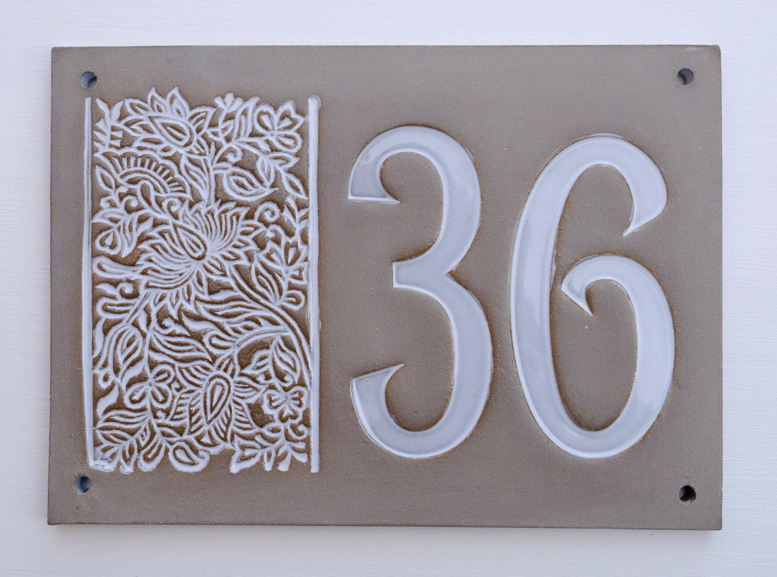 Rechteckiges graues Keramik-Hausschild mit erhabenen weißen Ziffern 36 und floralem Dekor