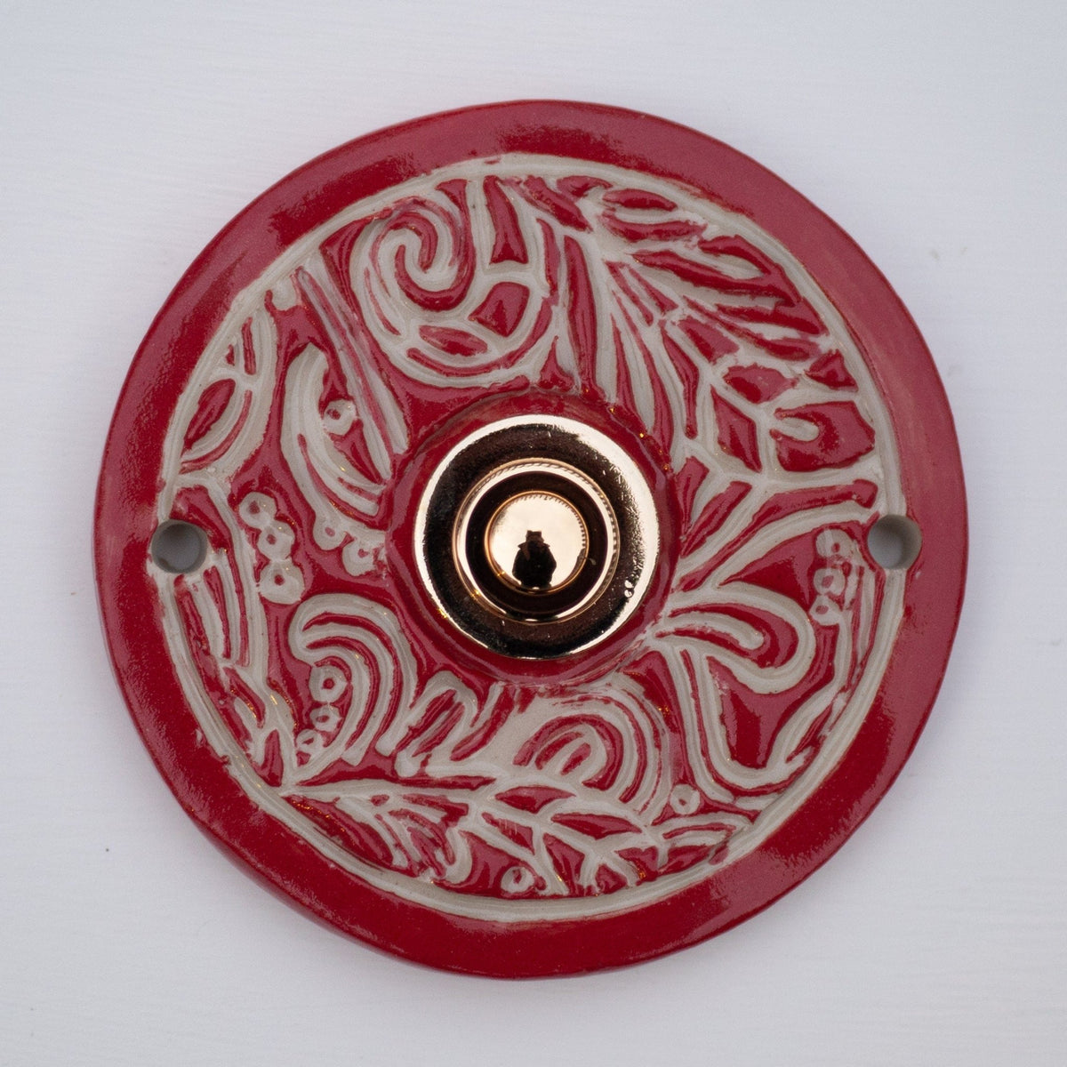 Runde keramische Klingel in glänzendem Rot mit weißen Ornamentmustern und bronzefarbenem Knopf
