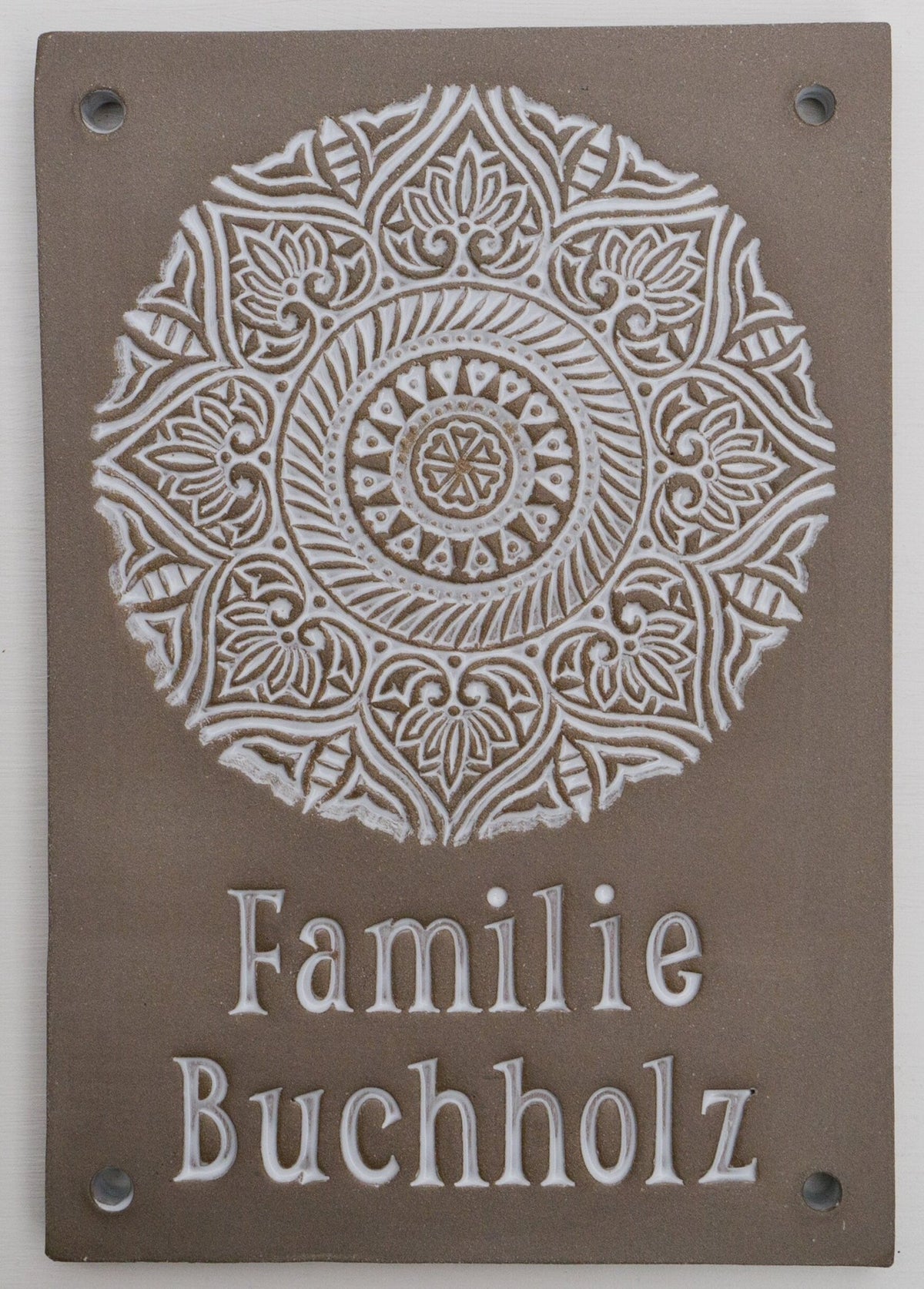 Rechteckiges taupefarbenes Keramik-Türklingelschild mit weißem Mandala-Ornament und graviertem Familiennamen Buchholz