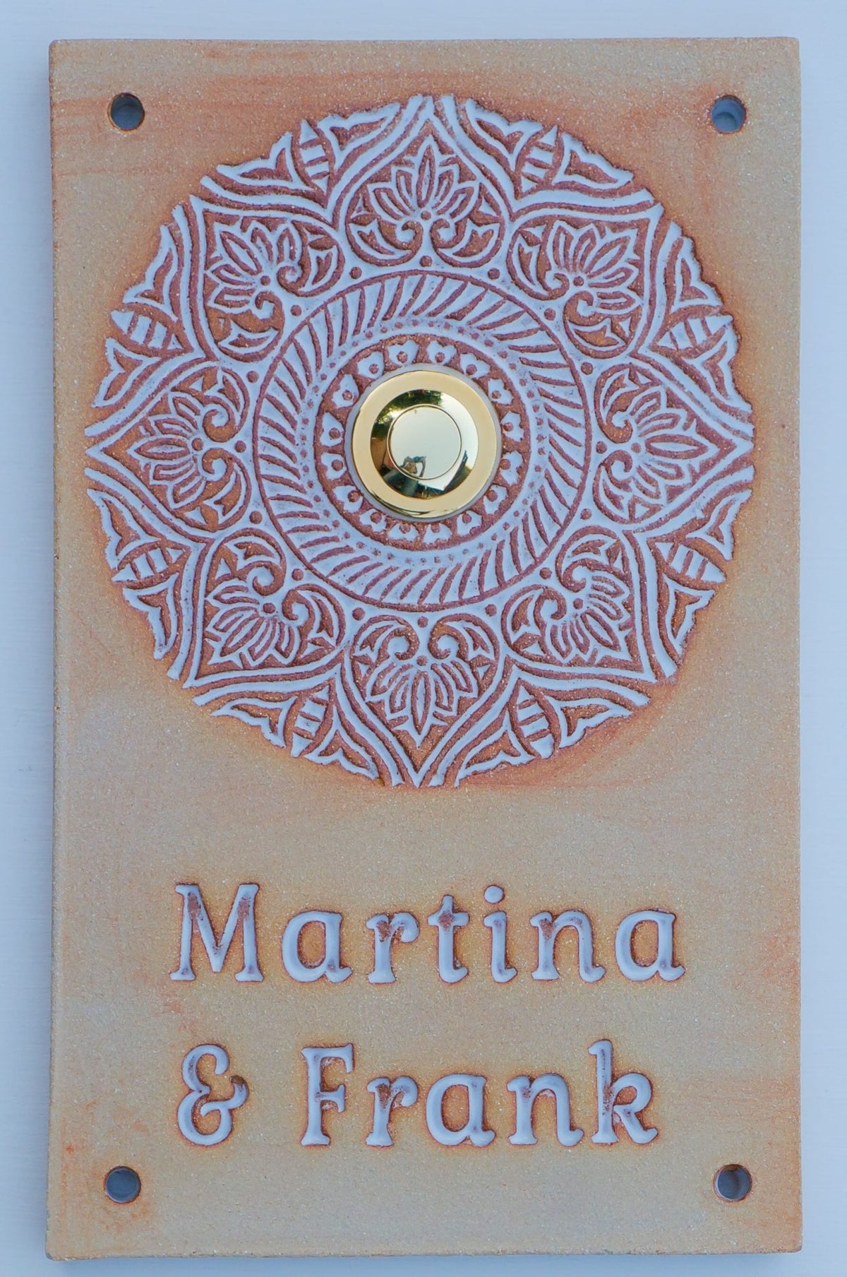 Rechteckiges terrakottafarbenes Keramik-Türklingelschild mit weißem Mandala-Ornament, goldenem Knopf und gravierten Namen Martina & Frank