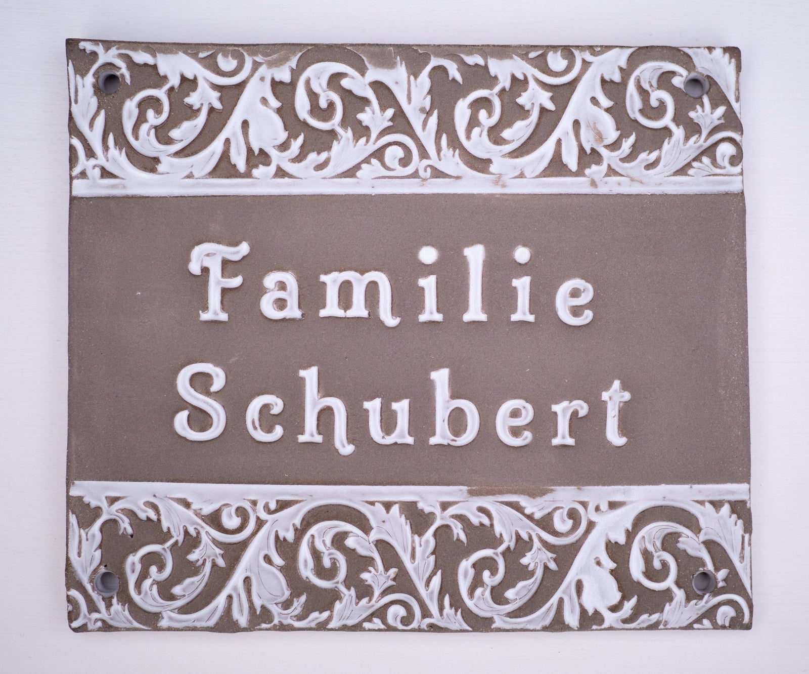 Handgefertigtes Terrakotta-Hausschild mit dekorativen weißen Ornamenten oberhalb und unterhalb des Namens Familie Seifert