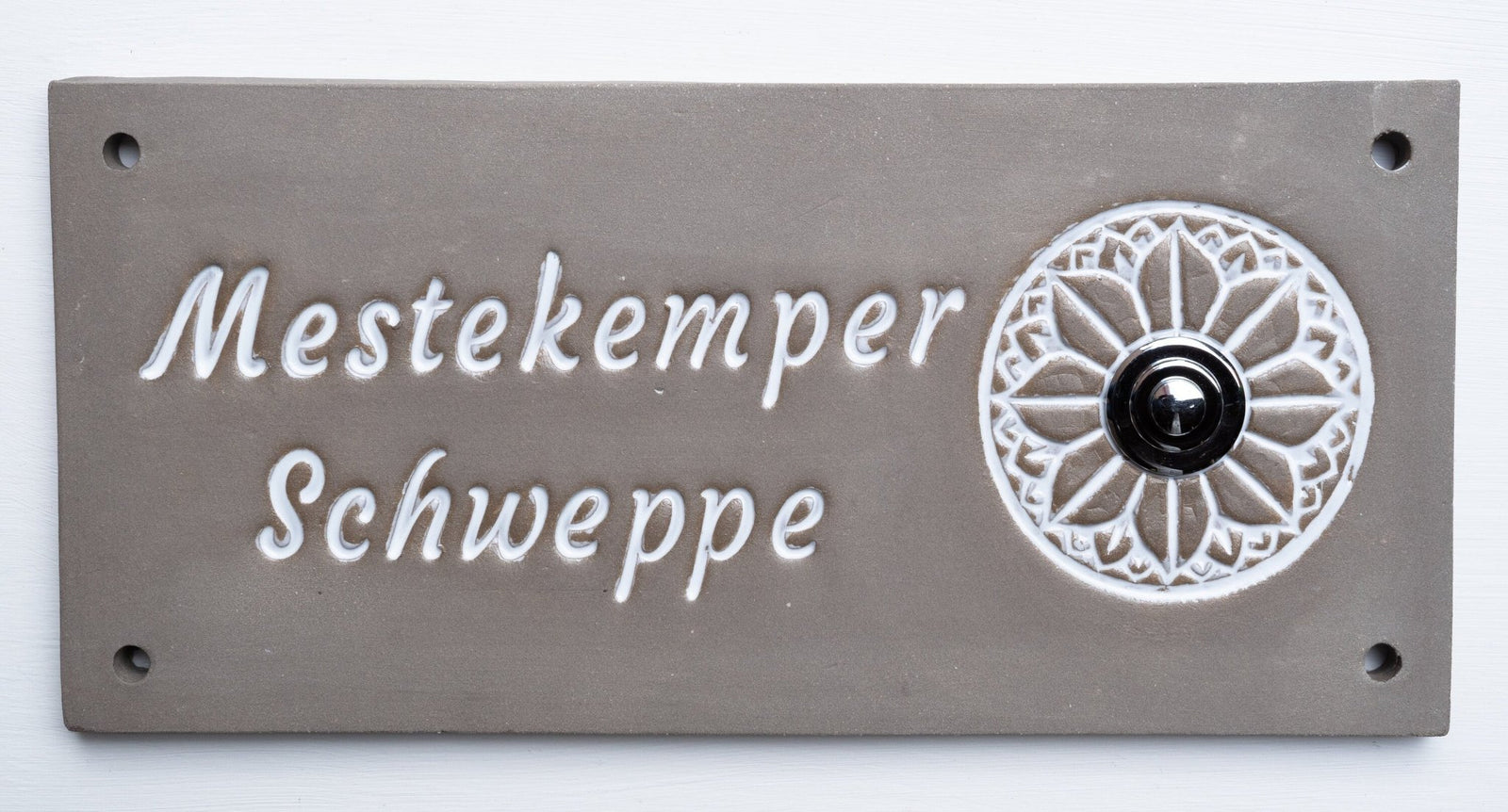 Rechteckiges graues Keramik-Türschild mit weißem Blumenornament, schwarzem Klingelknopf und Namen Mestekemper Schweppe